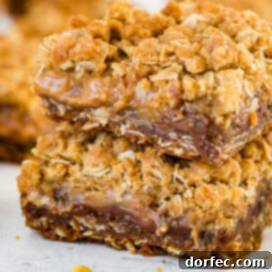 A single Carmelita bar, perfectly baked with golden oat crumble, gooey caramel, and chocolate peeking out.