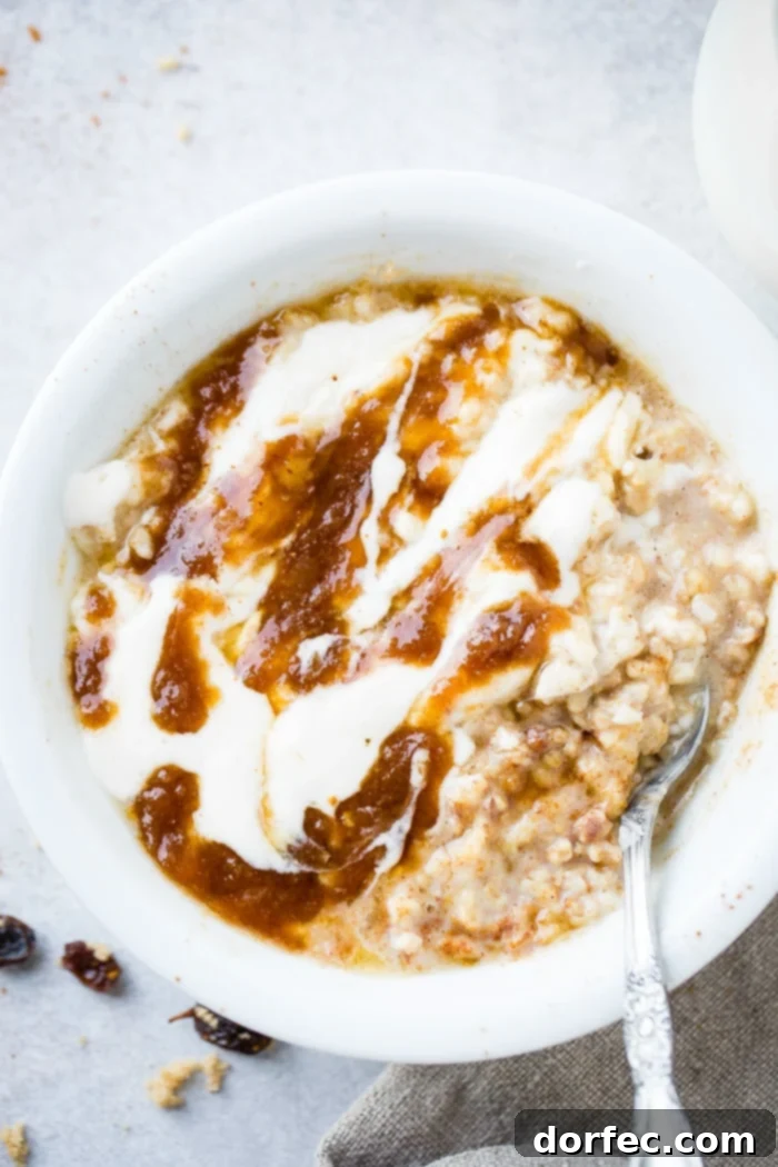 A vibrant, close-up shot of a bowl of lightened up cinnamon roll oatmeal, showcasing the luscious glaze, cinnamon swirl, and the texture of the oats, with scattered brown sugar, cinnamon, and raisins.