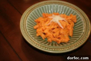 Close-up of creamy Roasted Red Pepper Pasta garnished with fresh herbs.