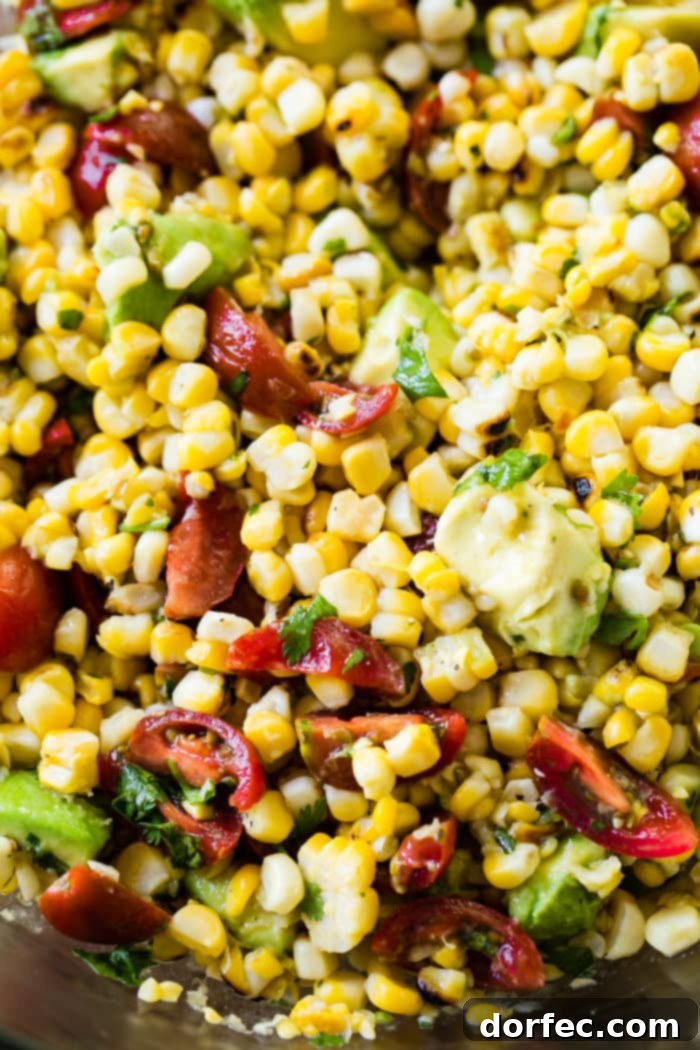 A vibrant close-up of a fresh grilled corn salad featuring juicy tomatoes and creamy avocado, showcasing the texture and color of the ingredients.