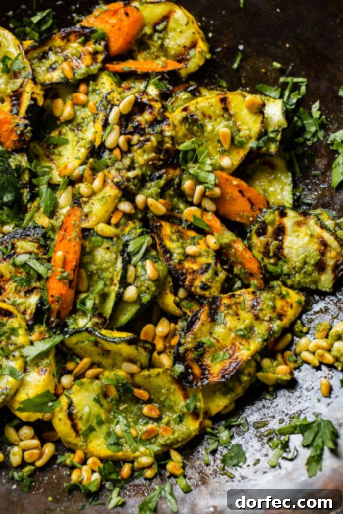 A vibrant platter of grilled vegetables, generously coated with pesto, garnished with parsley and toasted pine nuts. This visually appealing dish showcases the simple elegance and deliciousness of the 15-minute grilled veggies with pesto recipe.