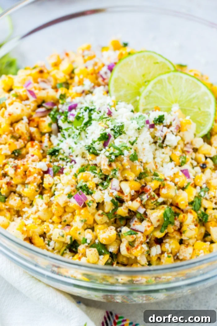 A vibrant glass bowl filled with grilled corn, red onions, cilantro, creamy Mexican crema, crumbled cotija cheese, and fresh lime juice makes for the perfect Elote Mexican Grilled Corn Salad, a staple for summer gatherings.