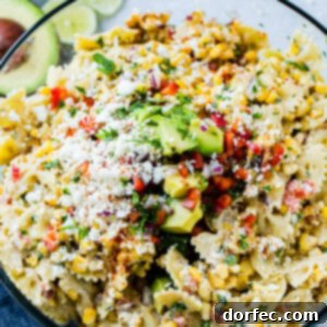 A close up photo of a bow tie pasta salad with avocados, peppers, grilled corn, cilantro, and cotija cheese making up an Elote Mexican Corn Pasta Salad