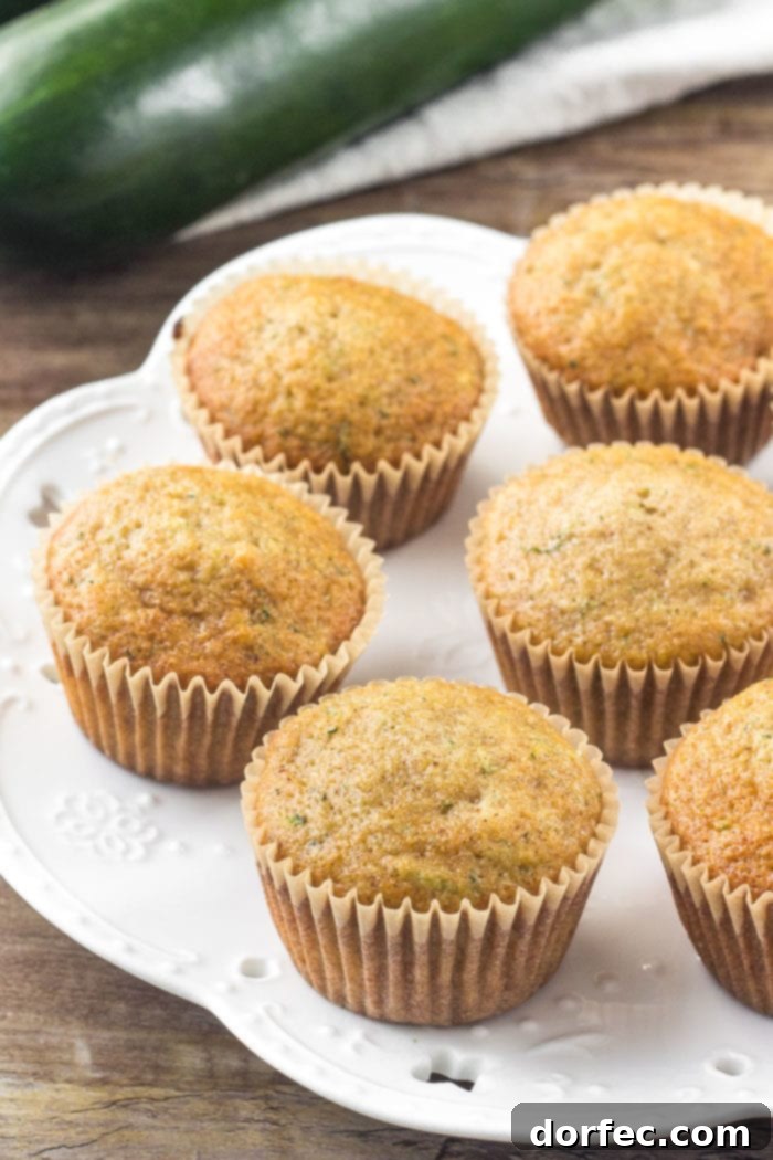 A beautifully arranged plate of freshly baked zucchini cupcakes, each topped with a generous swirl of fluffy cream cheese frosting, ready to be served.