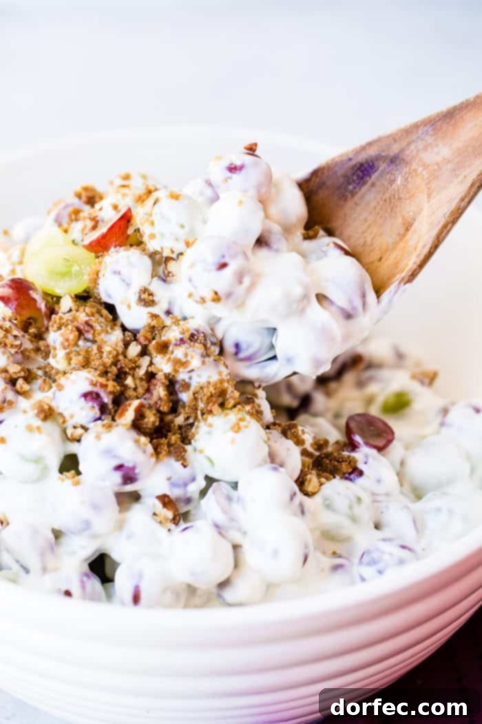 Southern Comfort Grape and Pecan Medley 3 An overhead shot of a white ceramic bowl filled with creamy Southern Grape Salad, garnished with a sprinkle of brown sugar pecans and a few artfully sliced grapes for visual appeal