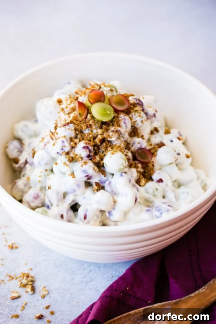 Southern Comfort Grape and Pecan Medley 4 A close-up of a white bowl of Southern Grape Salad, showcasing the creamy dressing coating the vibrant green and red grapes, with a generous sprinkle of brown sugar pecans on top