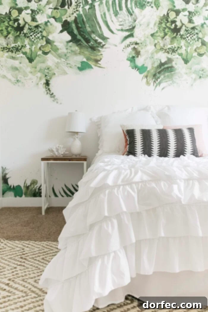 Simple white bed with modern palm leaf removable wallpaper accent wall in a beach themed tween room