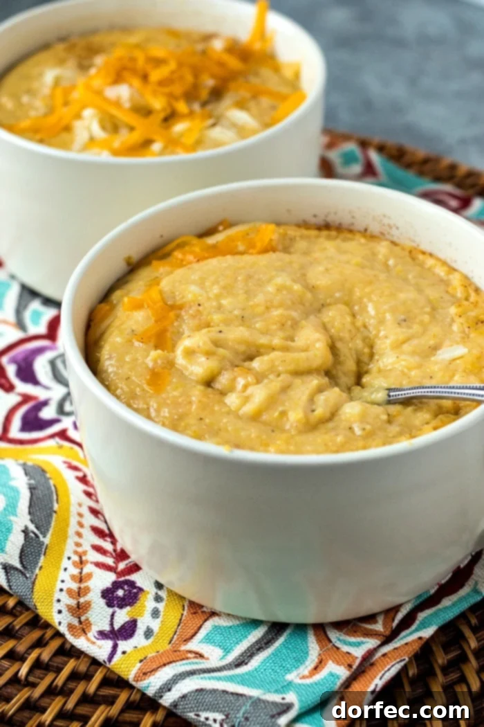 Creamy Southern Cheesy Grits 3 A close-up shot of thick, creamy, and visibly cheesy grits in a bowl, showing their rich texture and golden color. A spoon is poised, ready to scoop, highlighting the gooey cheese pull.