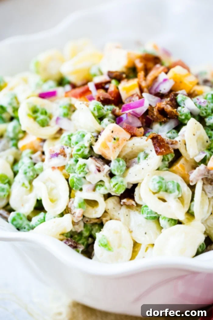 A vibrant Southern English Pea Pasta Salad featuring orchiette pasta, green peas, crispy bacon bits, and red onion, dressed to perfection.