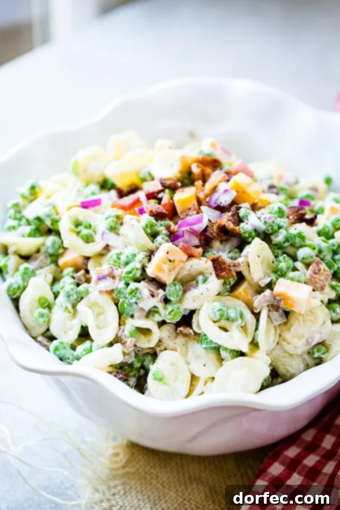 A large white bowl brimming with a delicious Easy Southern English Pea Pasta Salad, ready to be served at a BBQ or potluck.