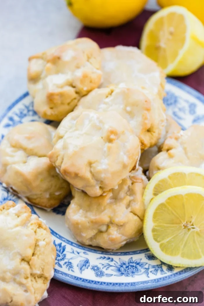 a pile of glazed lemon cookies on a blue floral vintage plate with slices of lemon