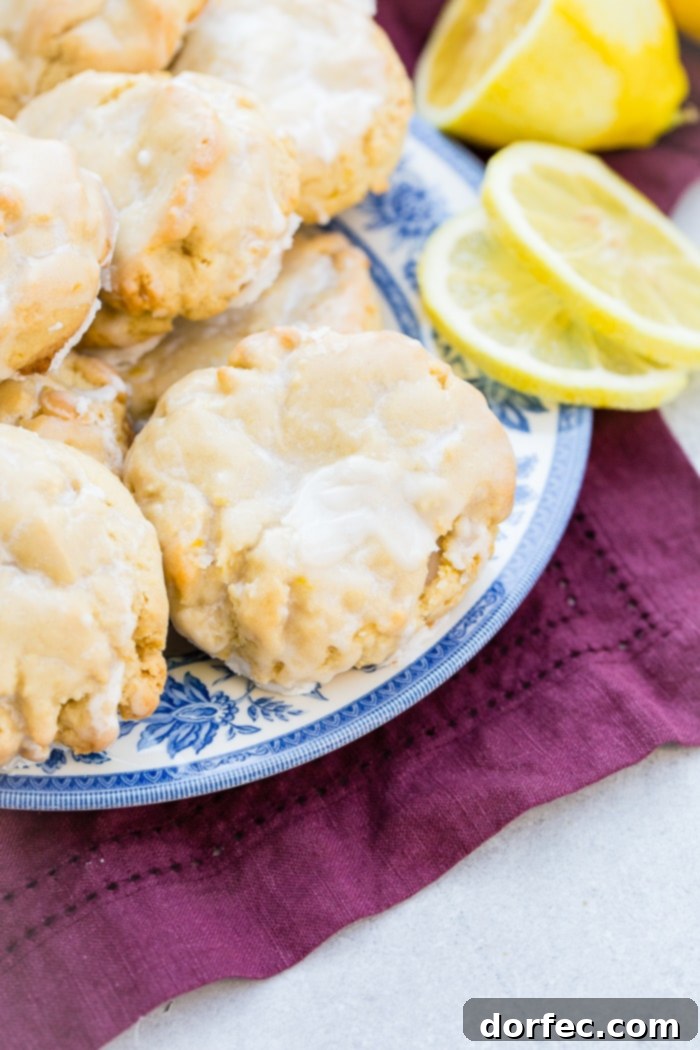 a pile of glazed lemon cookies on a blue floral vintage plate with slices of lemon