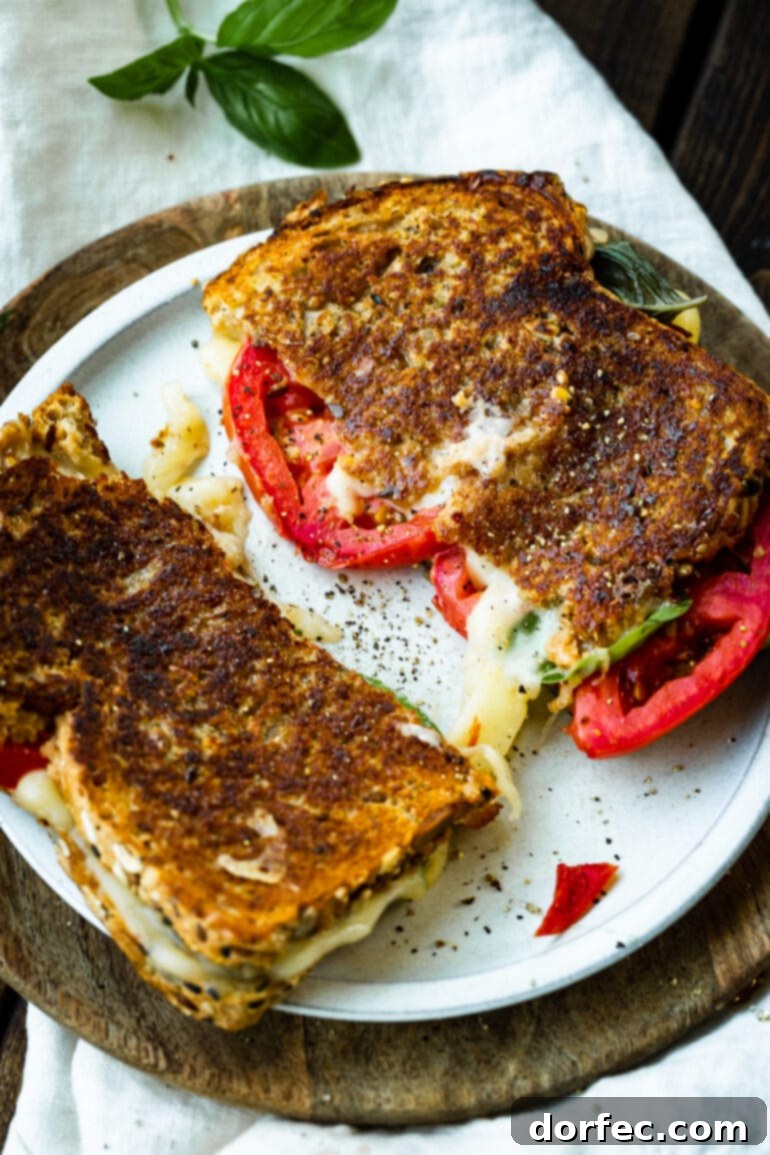 A perfectly grilled Havarti tomato basil grilled cheese sandwich, sliced diagonally and presented on a pristine white plate, showcasing the beautifully melted cheese and fresh fillings.