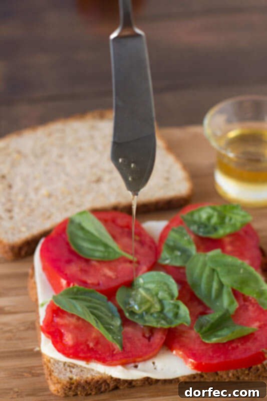 A close-up shot of Oprah's Favorite Grilled Cheese, showcasing the golden-brown whole wheat bread, melted Havarti cheese, and fresh tomato and basil layers. It's titled 