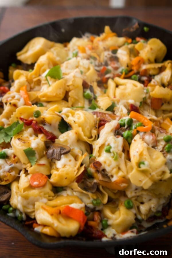 Close-up of golden brown pan fried tortellini with melted cheese and vegetables