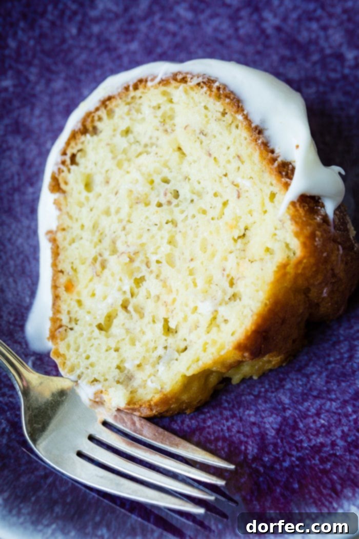 Heavenly Banana Bundt Cake 11 A slice of banana bundt cake with white creamy frosting on a blue plate.