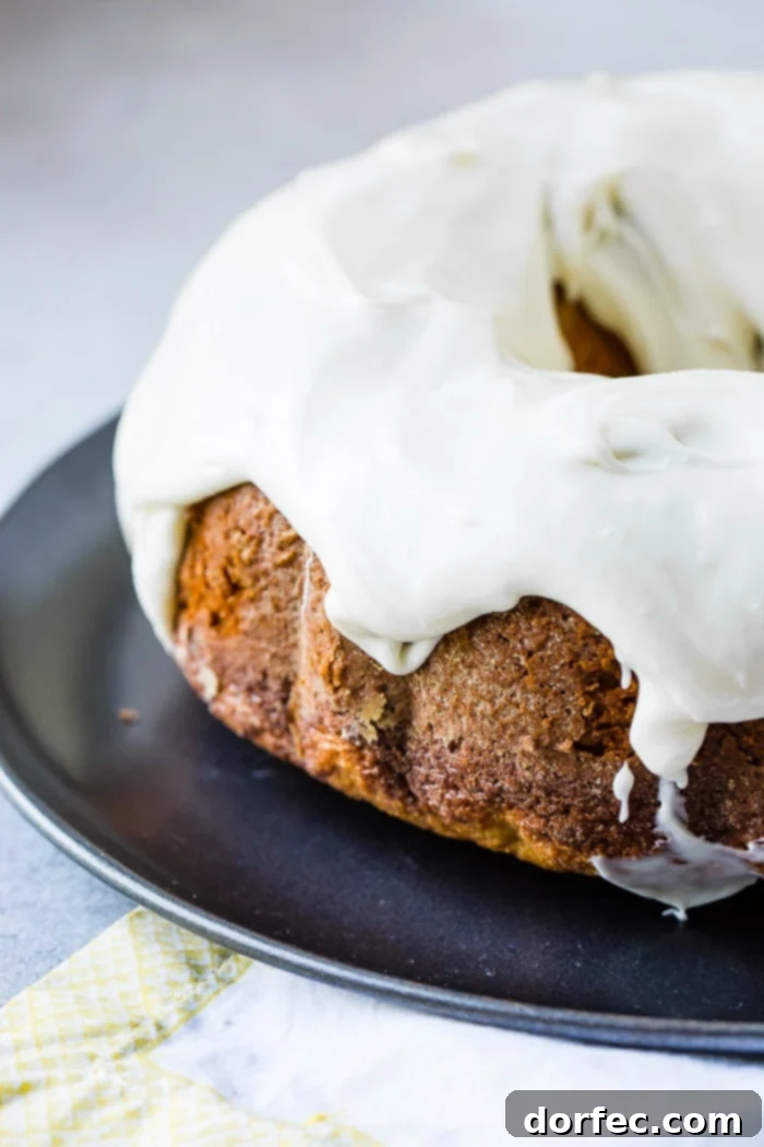 Heavenly Banana Bundt Cake 10 A dark grey platter with a banana pudding bundt cake slathered with cream cheese frosting