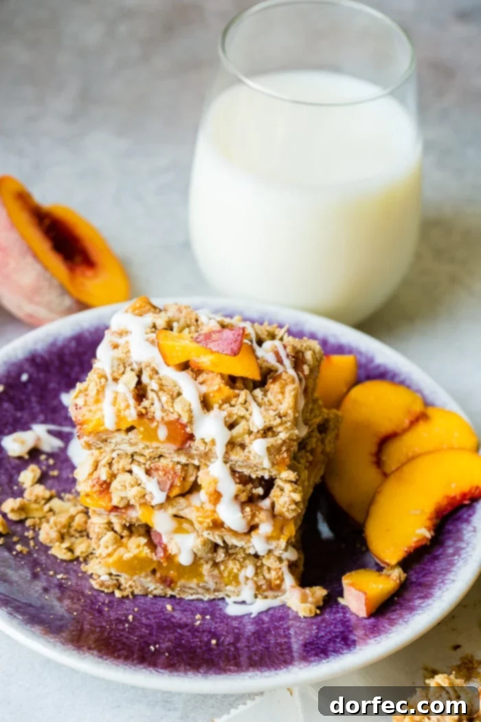 A dark purple plate with a stack of healthy peach oatmeal bars with a little glaze on top, with a glass of fresh milk in the background. The bars look enticing, showcasing a balance of health and deliciousness.