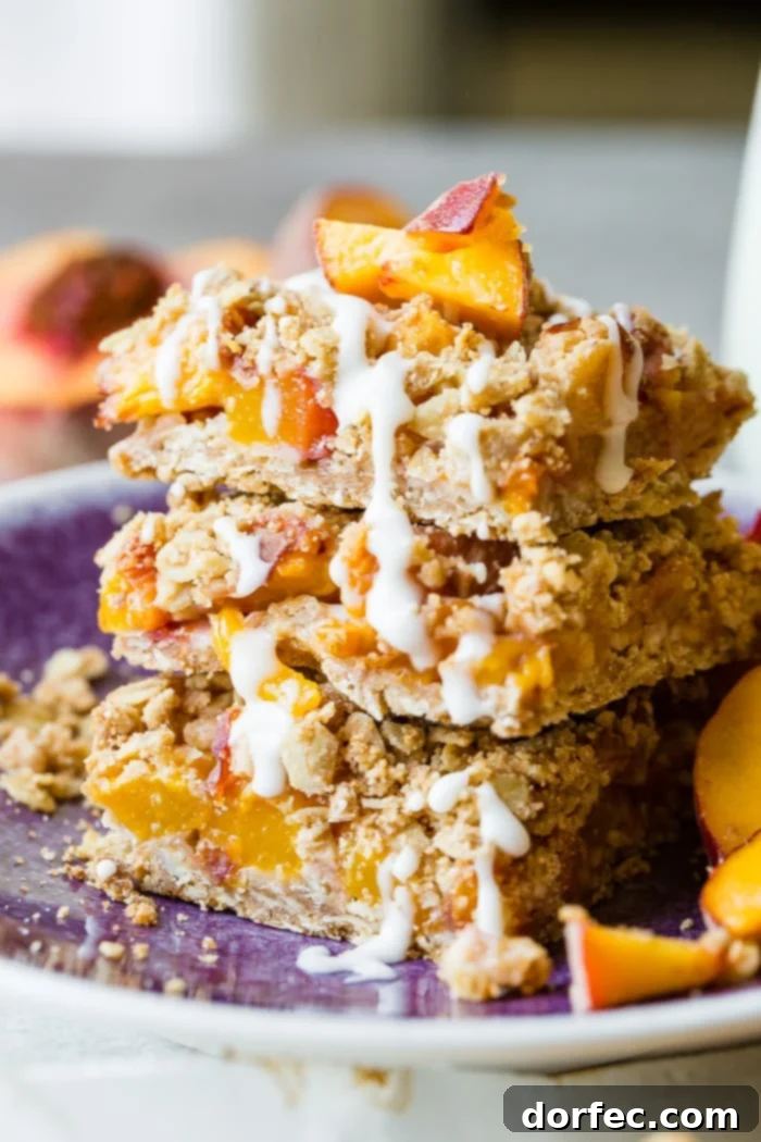 A close-up shot of a dark purple plate with a stack of healthy peach oatmeal bars, featuring a delicate glaze. The texture of the oats and the vibrant peach filling are visible.