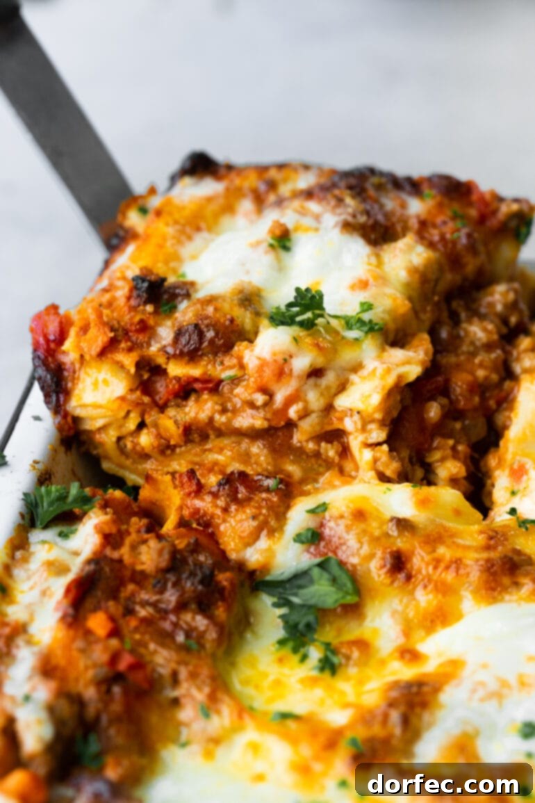 a photo of a serving of homemade meat lasagna being removed from a whole pan of lasagna