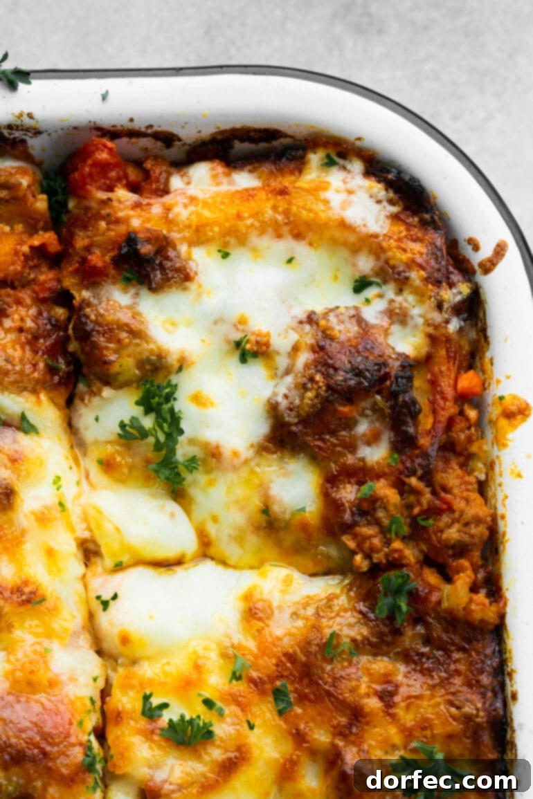 a photo of a baking dish of baked meat lasagna with a corner serving cut out