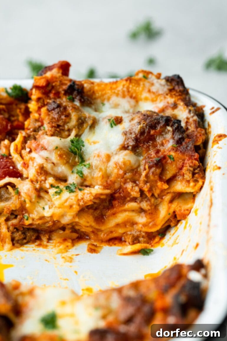 a photo of a serving of homemade meat lasagna sitting in a baking dish 