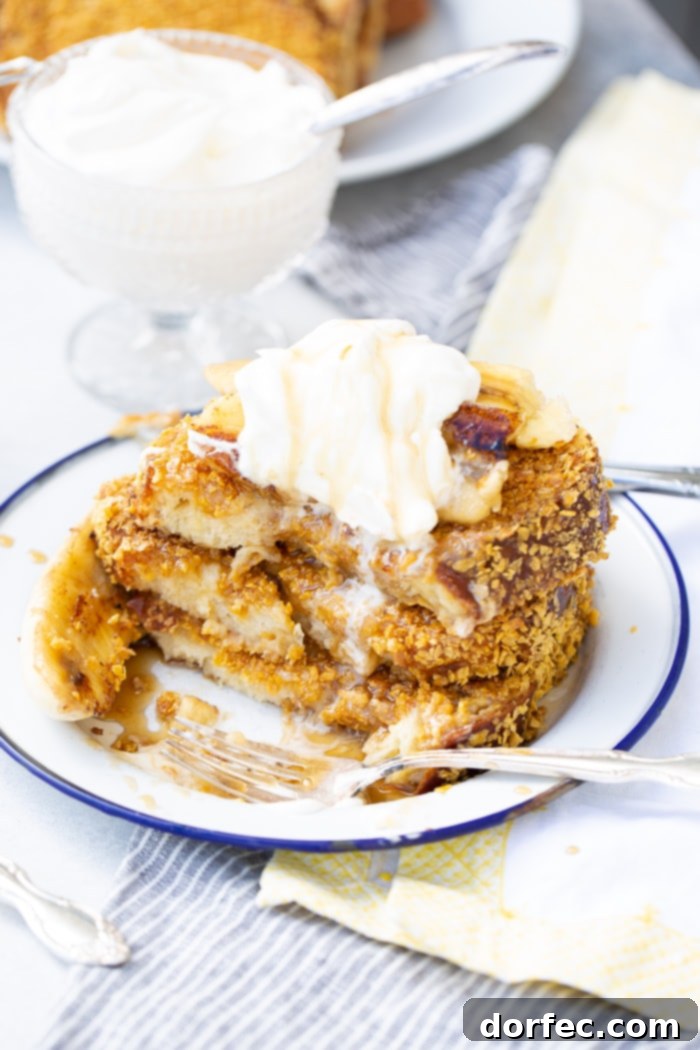 Cades Signature Bananas Foster French Toast 6 A generous stack of fluffy French toast, featuring a golden-brown cornflake crust, expertly drizzled with warm Bananas Foster syrup, and crowned with a cloud of whipped cream.