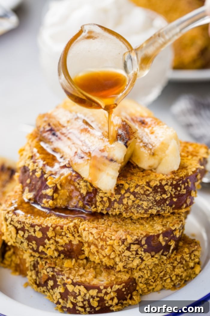 Cades Signature Bananas Foster French Toast 8 A captivating shot of golden-brown cornflake-crusted French toast being generously drenched in warm, glistening Bananas Foster syrup, creating an enticing cascade of sweetness.