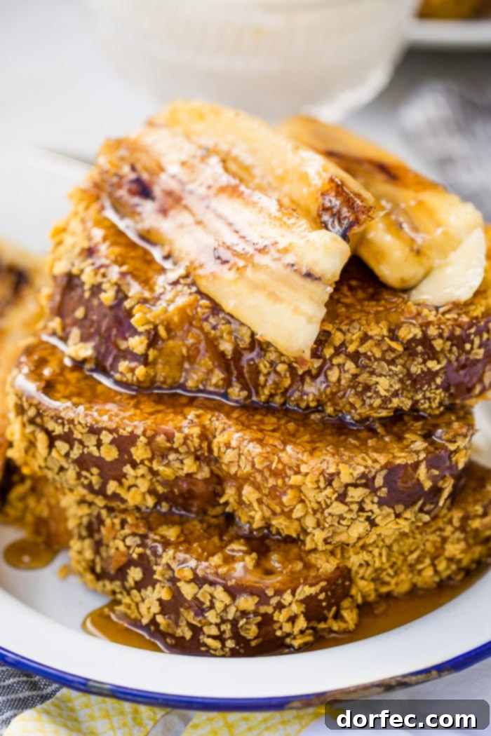Cades Signature Bananas Foster French Toast 10 A delightful close-up of cornflake-crusted French toast being gracefully drizzled with warm, golden Bananas Foster syrup, promising a perfect blend of crunch and sweetness.