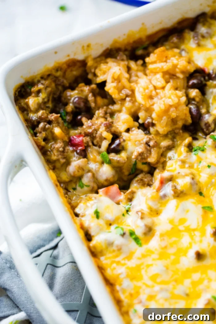 Cheesy Taco Rice and Beef Bake 3 A white casserole dish brimming with a vibrant Mexican casserole, ready to be served.