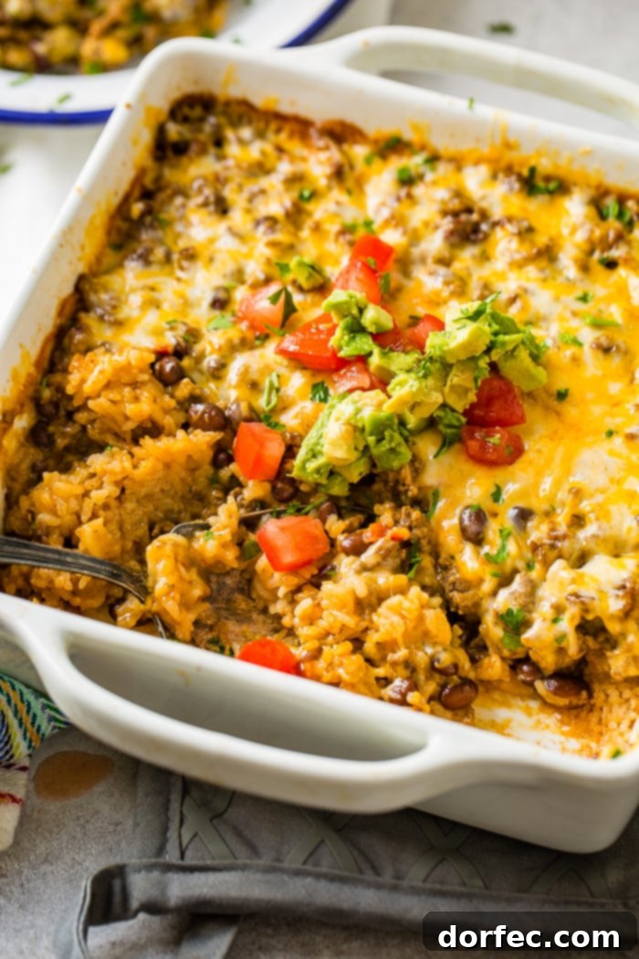 Cheesy Taco Rice and Beef Bake 5 A white casserole dish with a Mexican cheesy ground beef and rice casserole, perfectly baked with melted cheese.