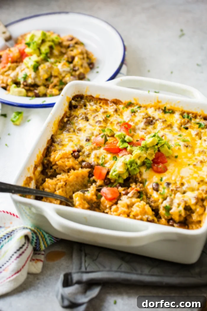 Cheesy Taco Rice and Beef Bake 6 A white casserole dish with a Mexican cheesy ground beef and rice casserole, close-up on the melted cheese.