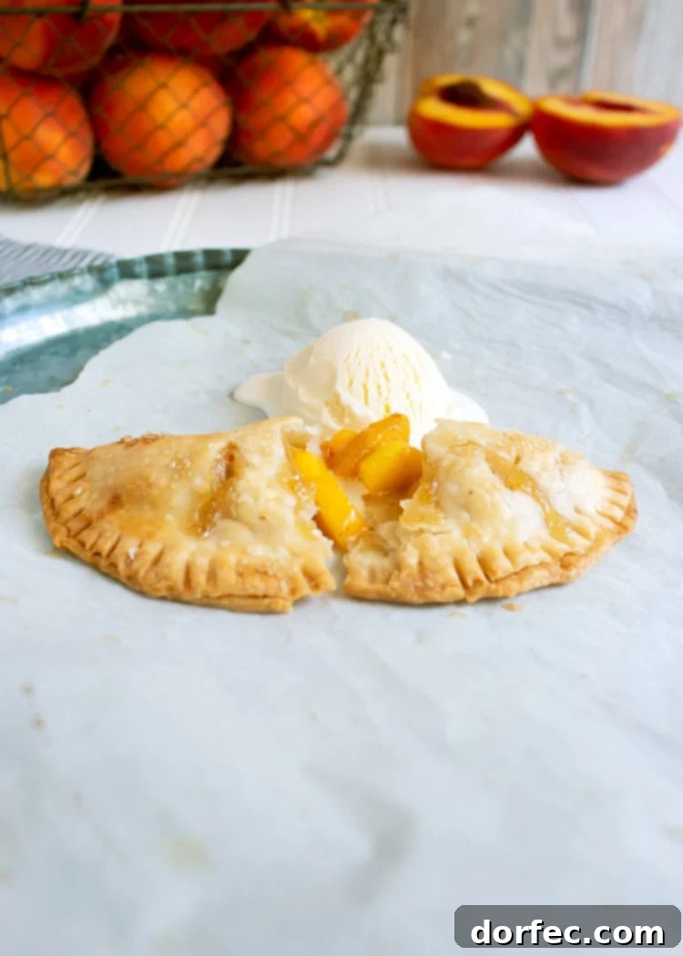 side view of peach hand pie that's been broken in half and topped with vanilla ice cream