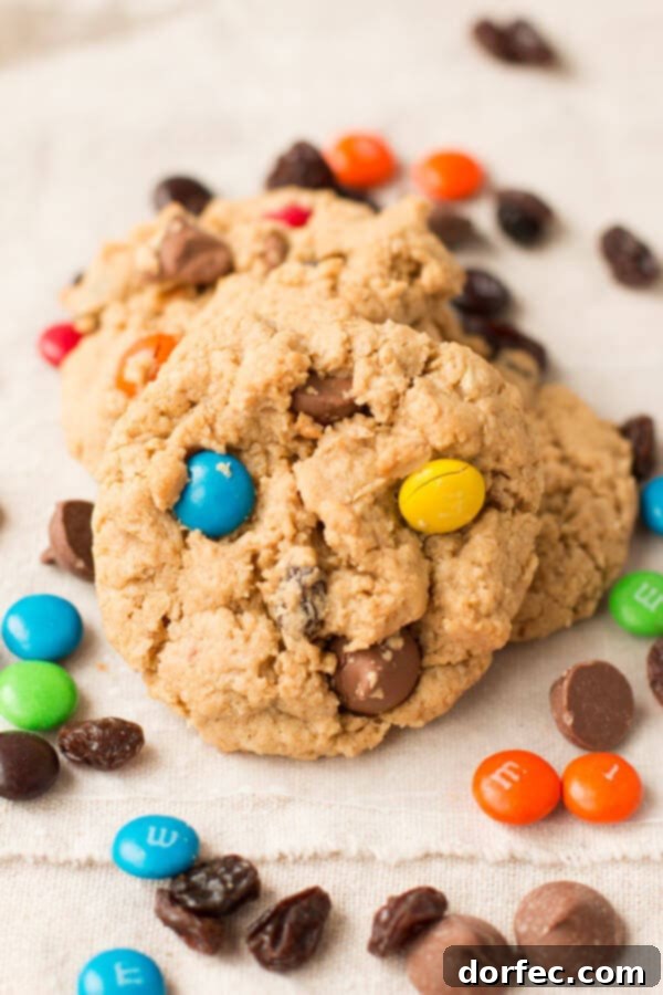 A fresh batch of Monster Cookies cooling on a wire rack, ready to be devoured. These cookies, packed with peanut butter, M&M's, and chocolate, are an irresistible treat for any occasion.