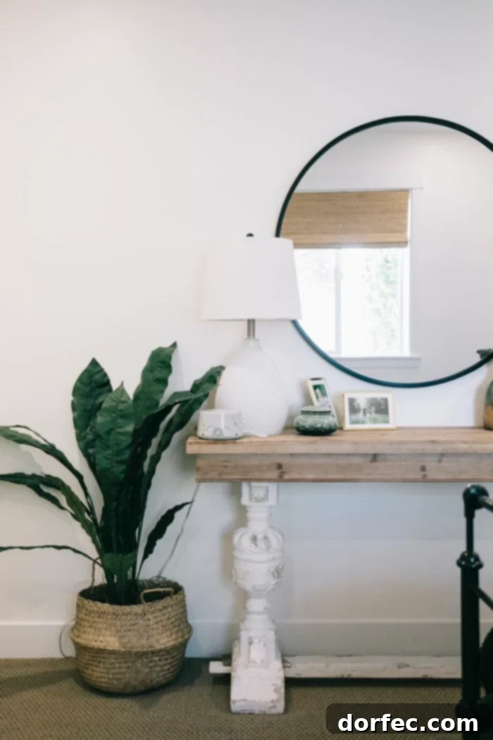A stylish black round mirror from Urban Outfitters positioned above a simple side table, complemented by a modern floor plant, adding a contemporary touch to the bedroom.