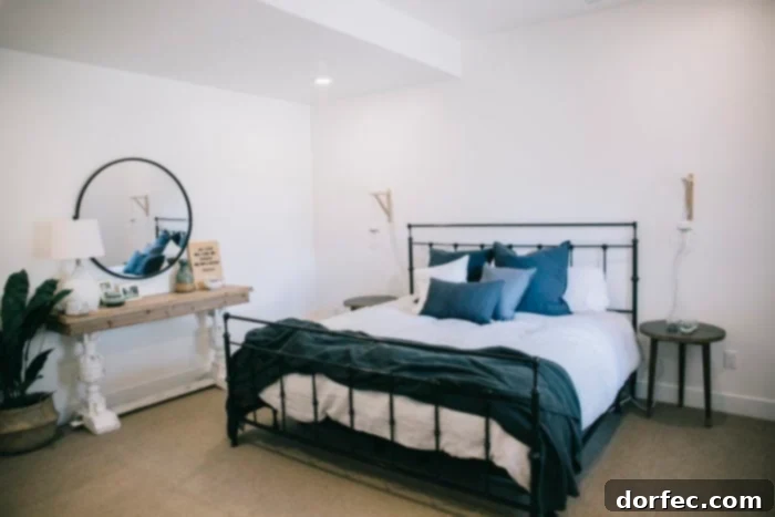 A close-up view of the chic black iron bed frame with a light grey duvet, complemented by an array of grey, blue, and white pillows, enhancing the modern aesthetic of the basement bedroom.