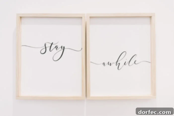 Two framed 'Stay Awhile' signs with elegant wood frames, adding a warm and welcoming touch to the guest bedroom decor.