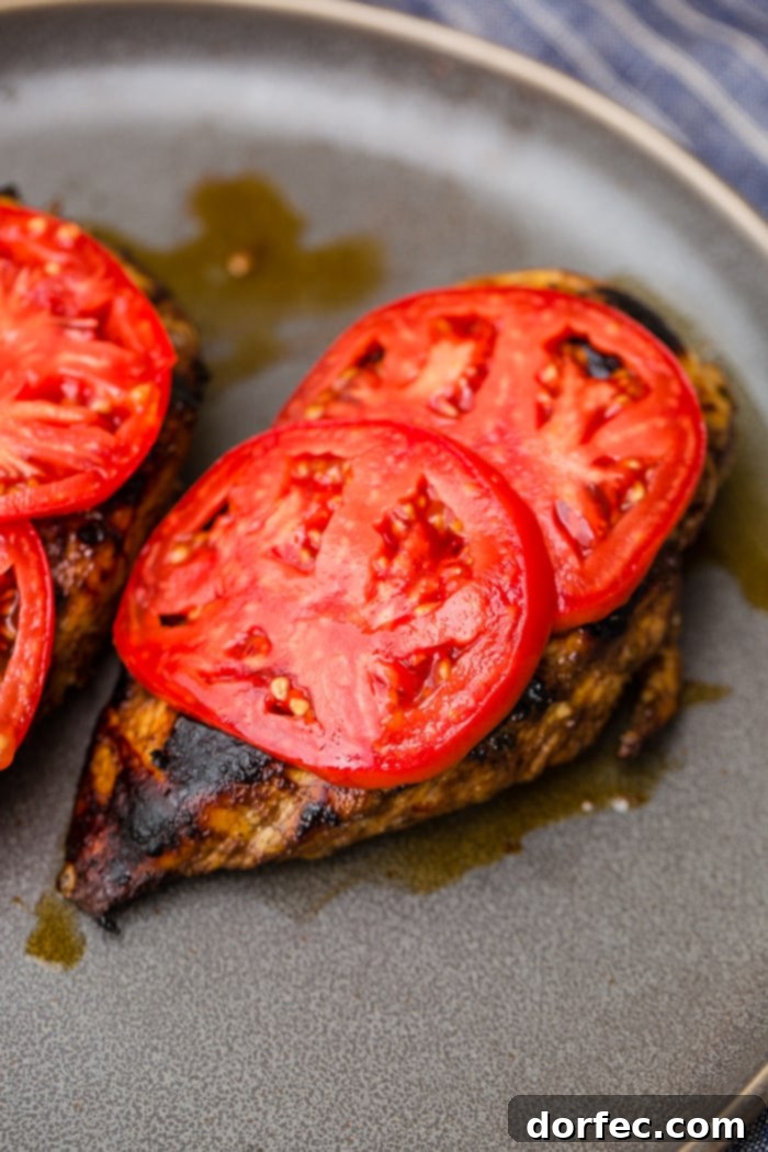 Close-up of a chicken breast with melted mozzarella, tomatoes, and basil
