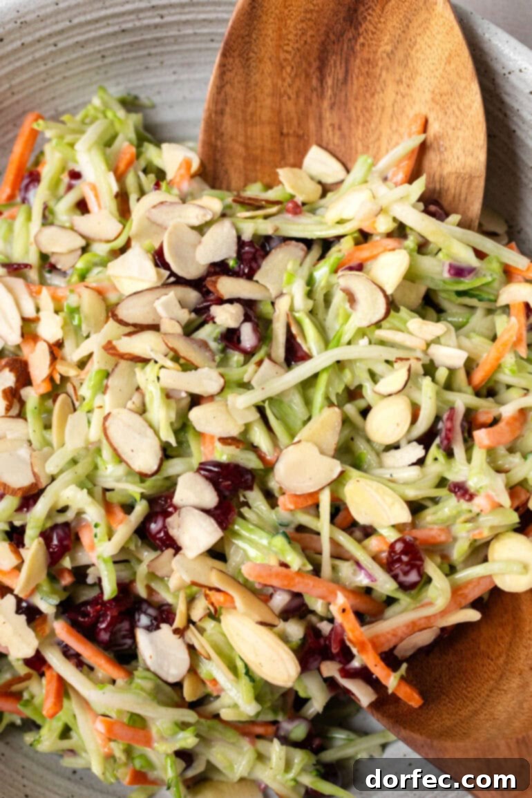 A photo capturing someone scooping up a generous serving of vibrant broccoli slaw, showcasing its texture and freshness.