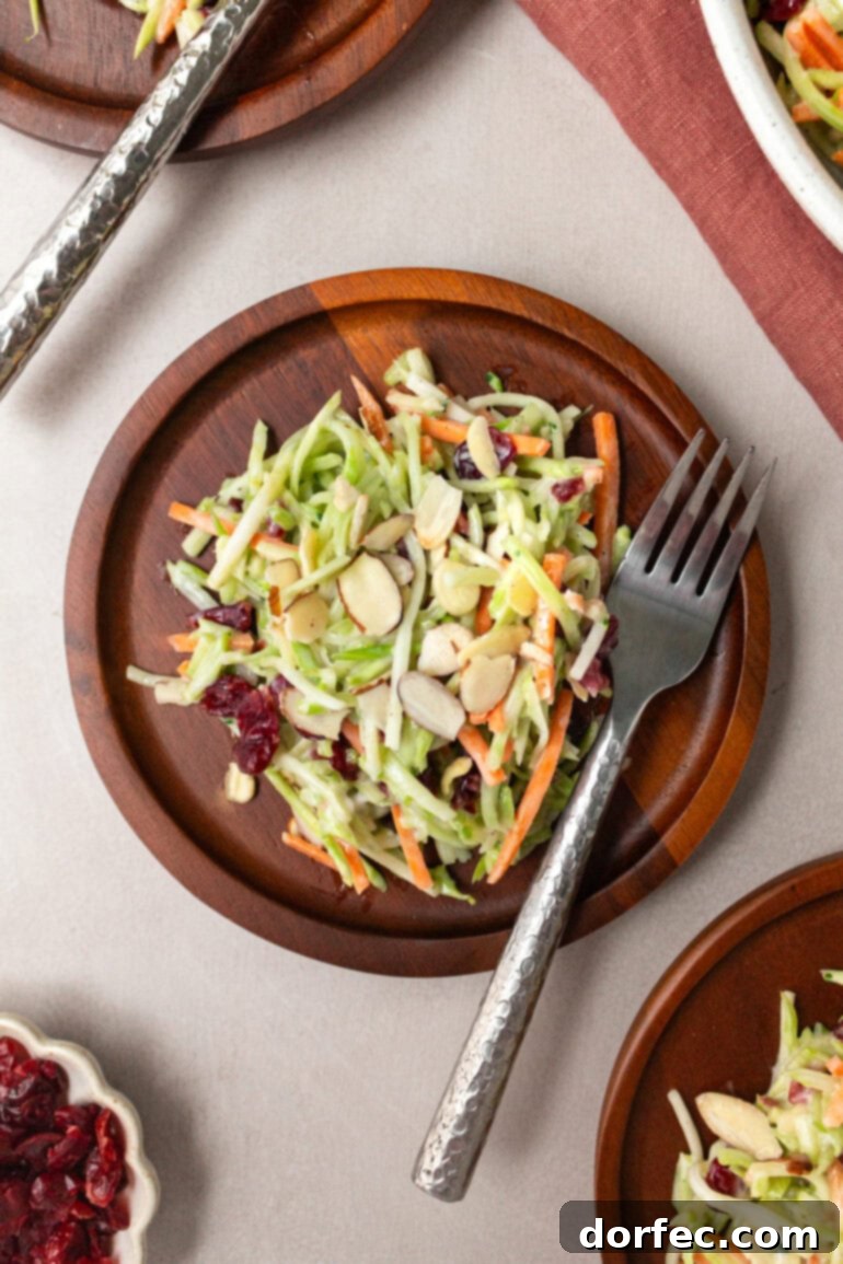 A small wooden salad plate holding a serving of broccoli slaw, with a fork ready to dig in.