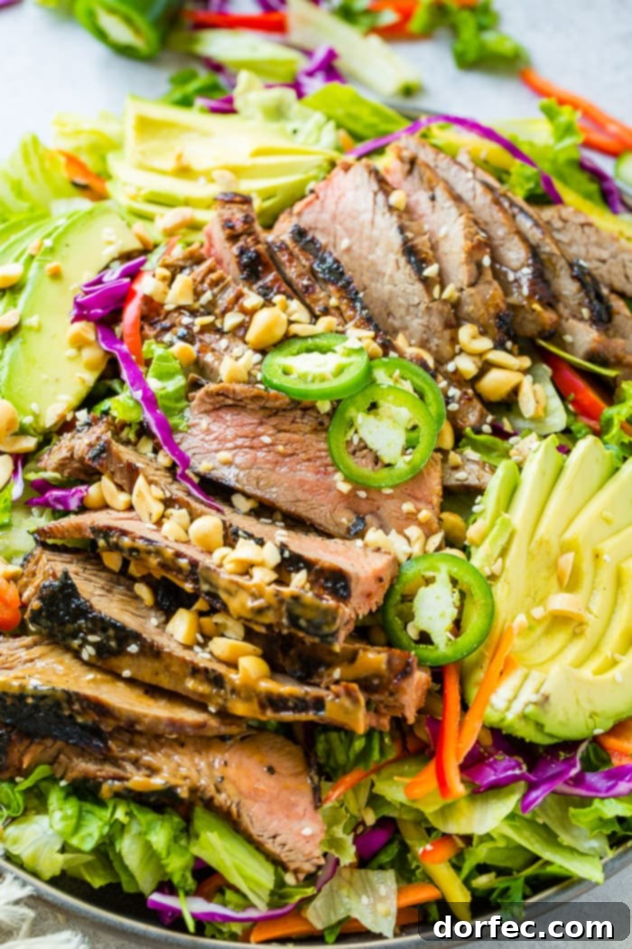 Zesty Thai Peanut Salad with Grilled Flank Steak 3 A vibrant plate featuring Healthy Thai Peanut Salad with Grilled Flank Steak, showcasing a rich medley of mixed greens, crisp vegetables, and flank steak marinated in a delectable Thai peanut sauce, all adorned with a ginger dressing and sesame seeds.
