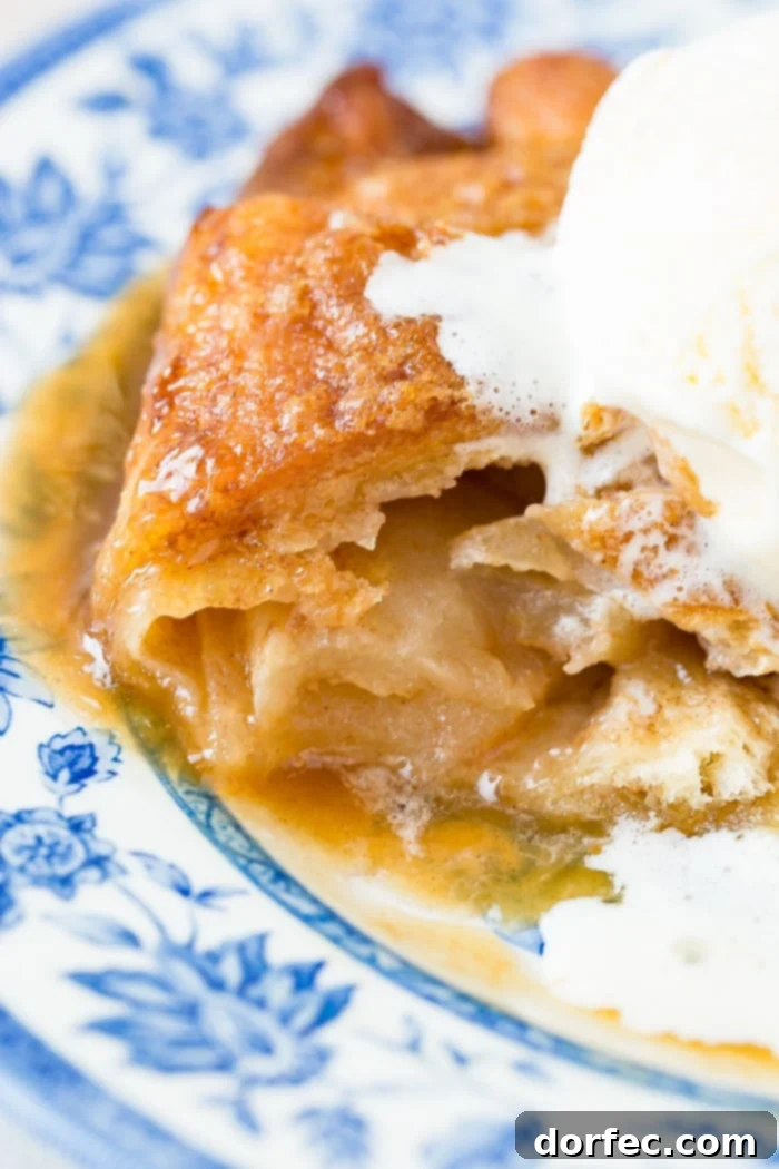 Sweet Simple Sprite Apple Dumplings 6 A close-up of two warm apple dumplings with caramel sauce and vanilla ice cream, ready to be enjoyed on a decorative blue plate.