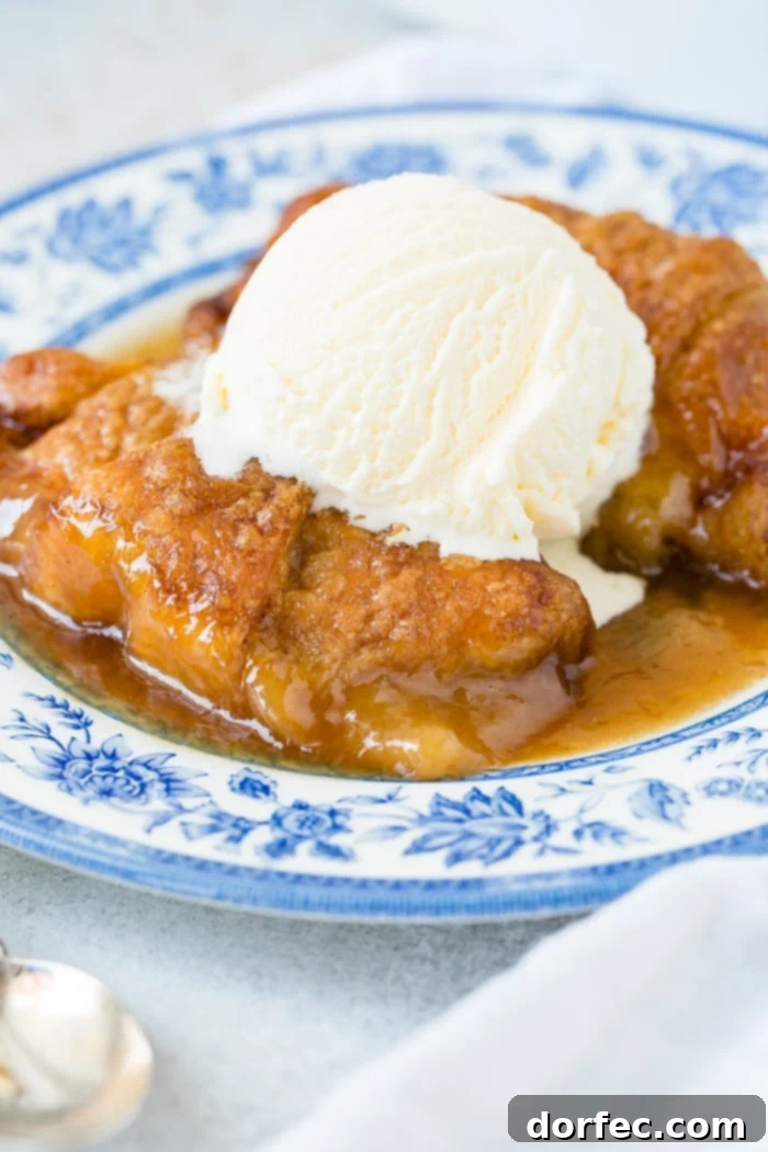 Sweet Simple Sprite Apple Dumplings 7 Two apple dumplings adorned with caramel sauce and vanilla ice cream, elegantly presented on a blue china plate, signifying a cherished family favorite dessert.