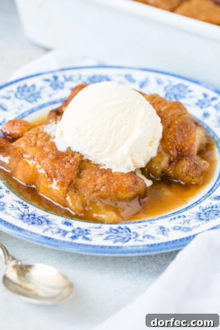 Sweet Simple Sprite Apple Dumplings 9 A final close-up of two warm apple dumplings, drenched in homemade caramel sauce and topped with vanilla ice cream, presented on a blue china plate for a truly delightful dessert experience.