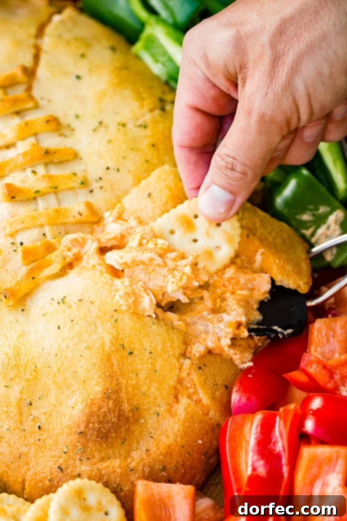 A cookie sheet with crackers, celery, peppers, and a football made out of crescent rolls and stuffed with buffalo chicken dip recipe