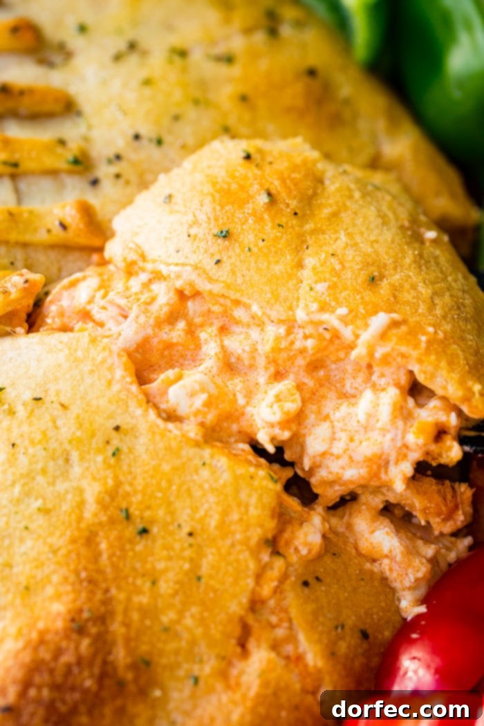 A cookie sheet with crackers, celery, peppers, and a football made out of crescent rolls and stuffed with buffalo chicken dip recipe