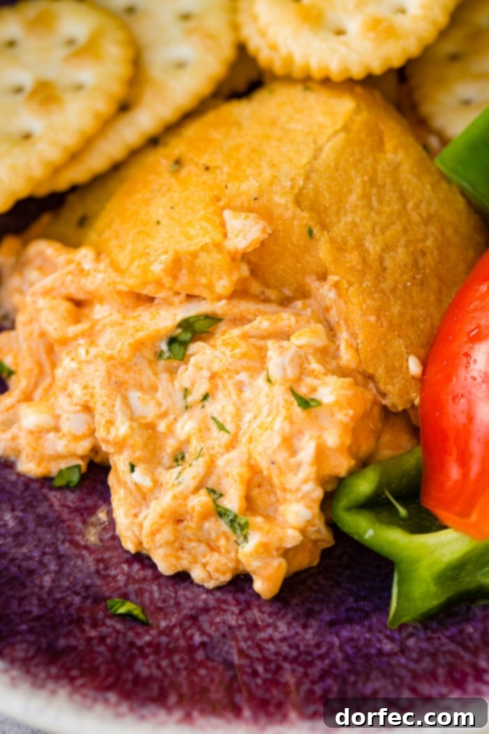 A cookie sheet with crackers, celery, peppers, and a football made out of crescent rolls and stuffed with buffalo chicken dip recipe