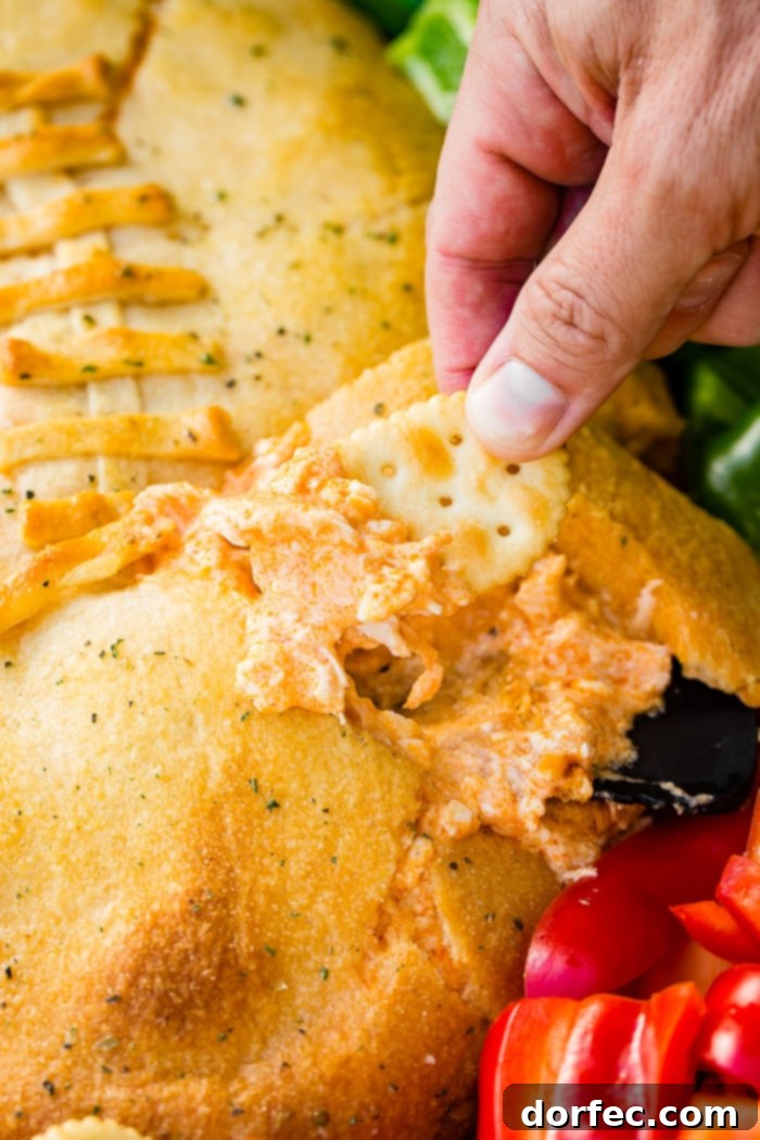 A cookie sheet with crackers, celery, peppers, and a football made out of crescent rolls and stuffed with buffalo chicken dip recipe