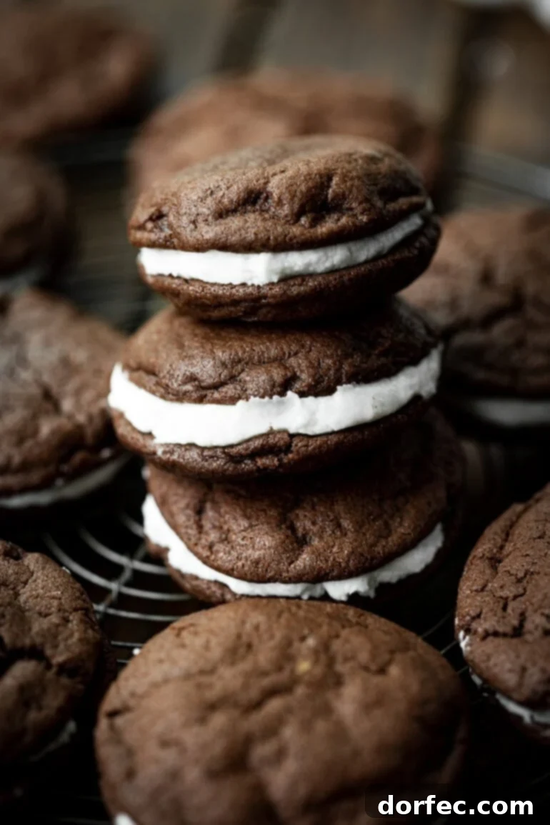 A photo of a stack of three homemade Oreo cookies, with additional cookies scattered around on a surface, highlighting their tempting layers.