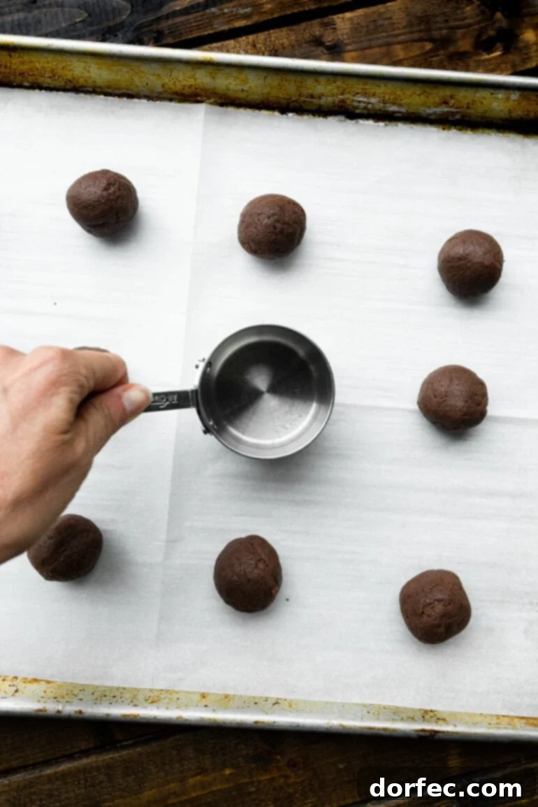 A close-up photo showing the rich, dark chocolate cookies, some with a hint of the creamy white filling, on a rustic background.